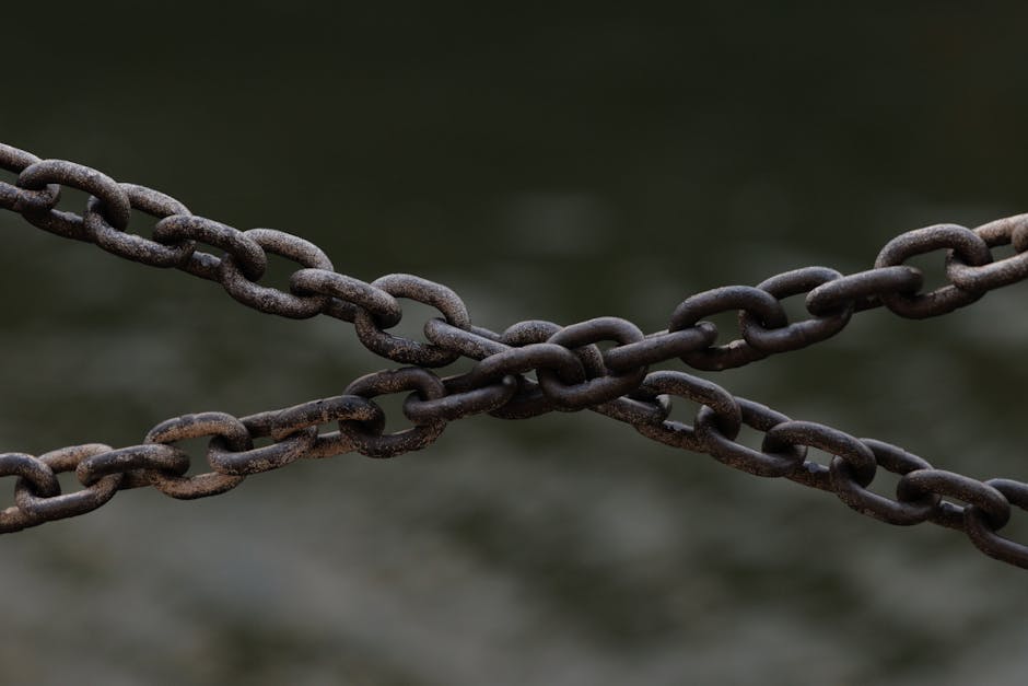 Close-up of crossed rusty chains over a blurred green background.